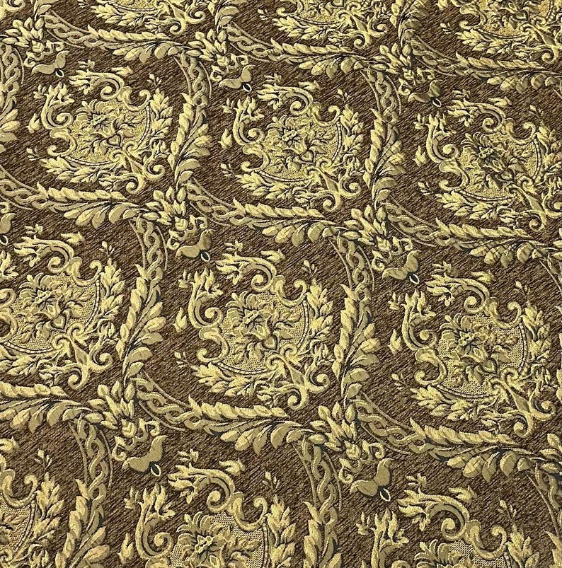 Puede incluir: Primer plano de una tela de damasco marr&oacute;n y dorada. El patr&oacute;n presenta dise&ntilde;os florales y de volutas ornamentados, creando una apariencia lujosa y texturizada. La tela es adecuada para tapicer&iacute;a o fines decorativos.