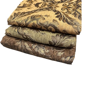 Puede incluir: Tres piezas de tela dobladas con un estampado de damasco floral. La pieza superior es de color beige y marr&oacute;n, la pieza central es de color verde oliva y marr&oacute;n, y la pieza inferior es de color marr&oacute;n y dorado. La tela tiene un aspecto texturizado.