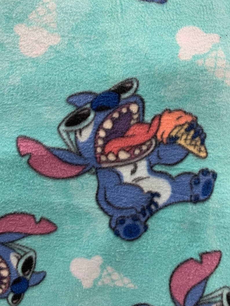 May include: Blue Stitch character with sunglasses and a pink tongue eating an orange and white ice cream cone on a turquoise background with white clouds.