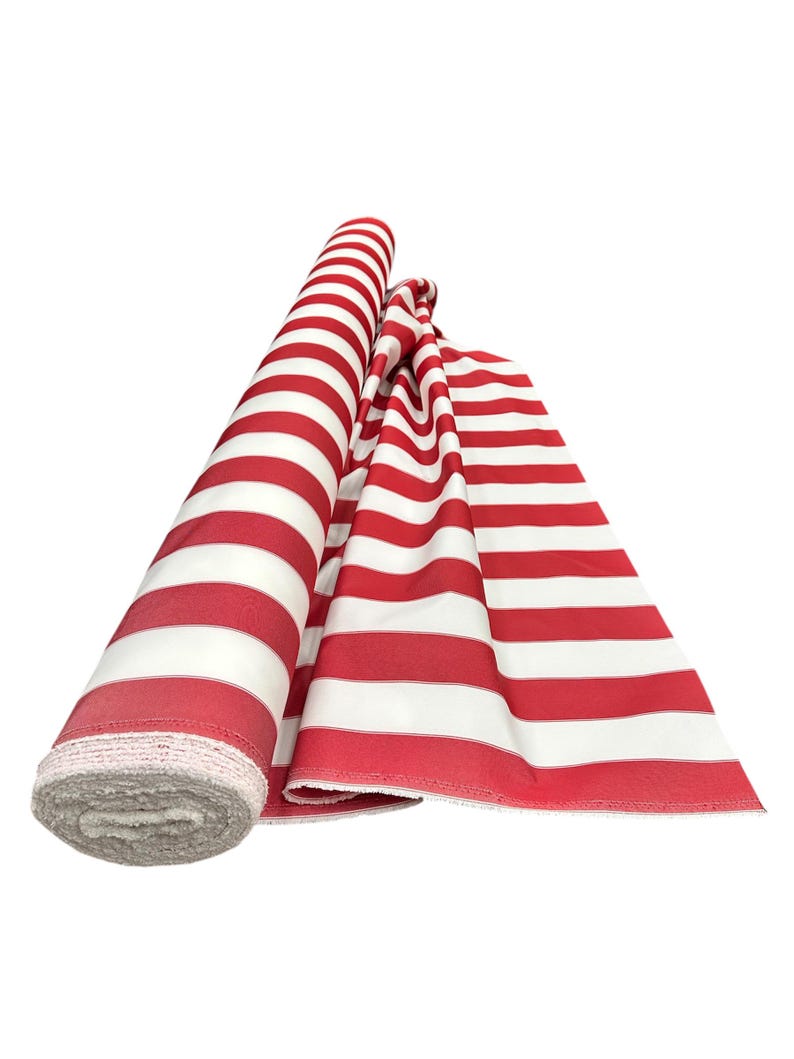 May include: A roll of red and white striped fabric, partially unrolled. The fabric is a bold red with wide white stripes. The edge of the rolled fabric shows a gray, textured material. The fabric is likely used for sewing or crafting projects.