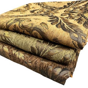 Puede incluir: Tres piezas de tela dobladas con intrincados dise&ntilde;os florales. La tela superior es de color canela con detalles en marr&oacute;n oscuro y dorado. La tela del medio es verde oliva con detalles dorados y marrones. La tela inferior es marr&oacute;n con dorado y marr&oacute;n oscuro.
