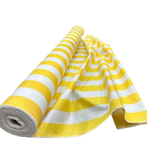 May include: A roll of yellow and white striped fabric is partially unrolled, revealing the pattern. The fabric is a bright yellow with wide white stripes. The fabric is likely used for sewing or crafting projects.