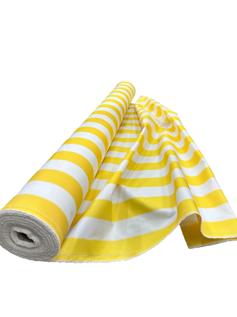 May include: A roll of yellow and white striped fabric is partially unrolled, revealing the pattern. The fabric is a bright yellow with wide white stripes. The fabric is likely used for sewing or crafting projects.