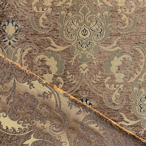 May include: Close-up of a brown fabric with a gold and green damask pattern. The fabric has a textured surface and a subtle sheen.