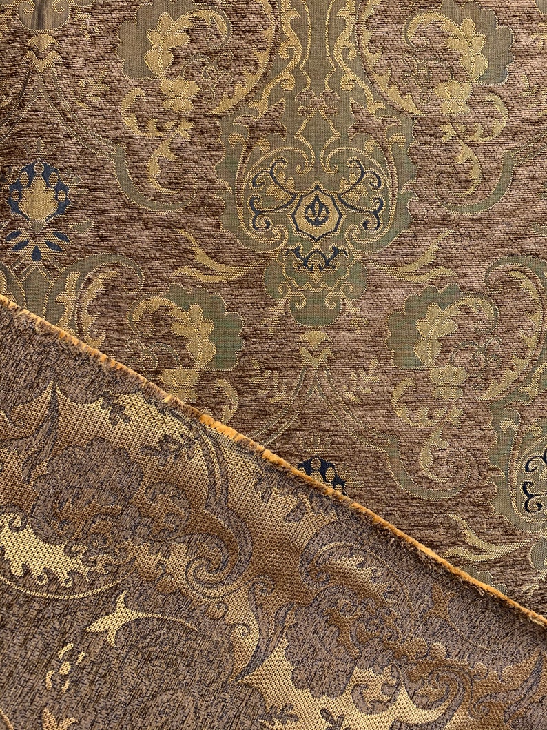May include: Close-up of a brown fabric with a gold and green damask pattern. The fabric has a textured surface and a subtle sheen.