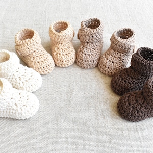 Pode incluir: Seis pares de sapatinhos de beb&eacute; em croch&ecirc; branco, bege e castanho. Os sapatinhos t&ecirc;m fecho de bot&atilde;o e est&atilde;o dispostos em semic&iacute;rculo.