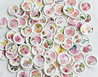 May include: A collection of white round stickers with various floral designs. Each sticker features a different floral pattern in shades of pink, white, and green.
