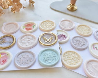 May include: Assortment of 16 wax seals with various designs, including floral, geometric, and a butterfly. The seals are in shades of pink, white, blue, and gold.
