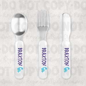 May include: A set of three personalized children's cutlery with white handles, blue dinosaur graphics, and the name "Braxton" in purple lettering.
