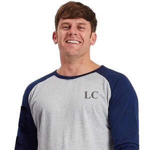 May include: A gray and navy blue long-sleeved pajama top with a blue and gray plaid pajama bottom. The top has a baseball style design with navy blue sleeves and a gray body. The top has the letters "LC" embroidered on the chest.