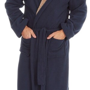 May include: A navy blue hooded robe with a brown sherpa lining. The robe has a belt and two pockets. The name "Josh" is embroidered on the robe.