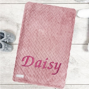 May include: A soft pink baby blanket with a herringbone pattern and the name "Daisy" embroidered in pink.