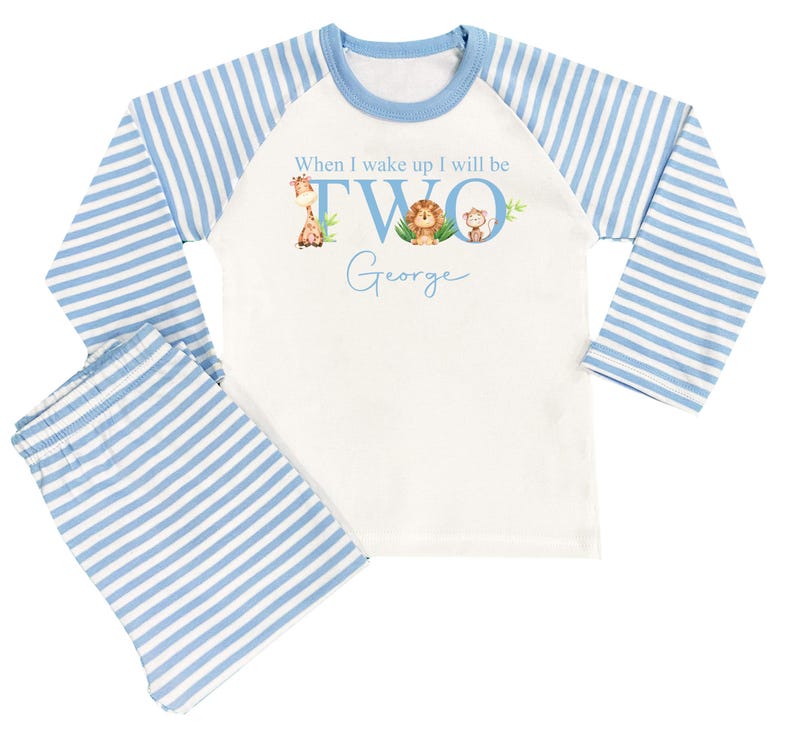 May include: White and blue striped pajamas with long sleeves. The top has a graphic of a giraffe, lion, and monkey with the text "When I wake up I will be TWO George".
