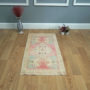 May include: A light pink and cream vintage rug with a floral pattern. The rug is on a wooden floor.