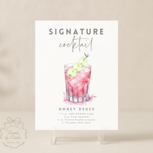 May include: A white sign with the words "SIGNATURE cocktail" in gray and a watercolor illustration of a pink cocktail with ice and melon balls. The sign also lists the ingredients for a "HONEY DEUCE" cocktail.