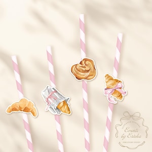 May include: Pink and white striped straws with watercolor illustrations of pastries, including croissants and a heart-shaped pastry. The straws are decorated with small stickers. The image includes the text "Events by Ericka".