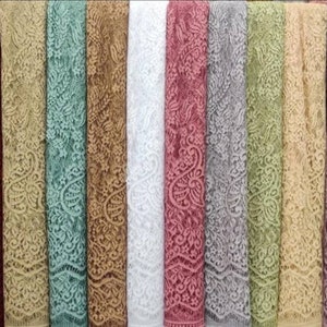 May include: A collection of ten lace fabric samples in various colours, including burgundy, beige, green, gold, white, pink, grey, light green, yellow, and purple. The lace has a delicate floral pattern.