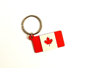 May include: A red and white Canadian flag keychain with a silver key ring. The flag has a white maple leaf in the center.