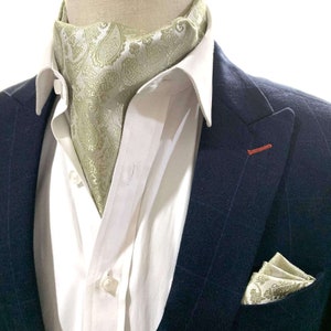 Puede incluir: Una camisa blanca de vestir para hombre con una corbata de estampado paisley verde y una chaqueta de traje azul marino con un pañuelo de bolsillo.