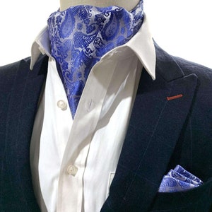 Op de afbeelding: Een blauwe en witte paisley-gepatroneerde das met een bijpassend zakdoekje. De das wordt gedragen met een wit overhemd en een donkerblauw colbert.