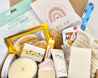 May include: A gift box filled with self-care items, including a foot mask, lip butter, body lotion, a candle, and a bath pouf. The box also includes a card with the text "Be Kind to Yourself Relax".