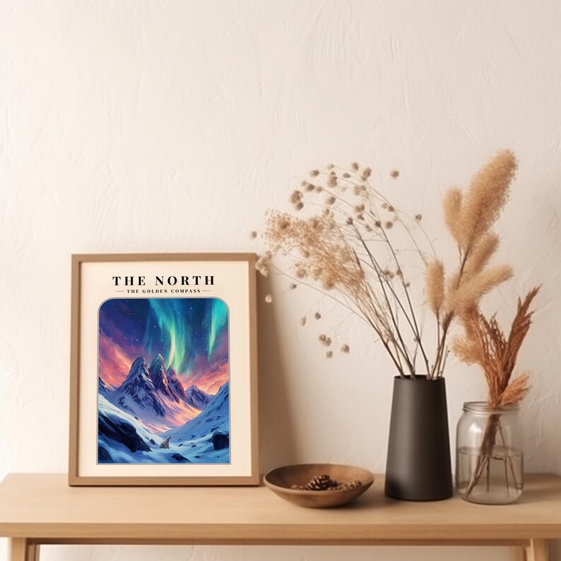 May include: Framed print of a snowy mountain landscape with a colorful aurora borealis in the sky. The text "THE NORTH - THE GOLDEN COMPASS" is at the top of the print.