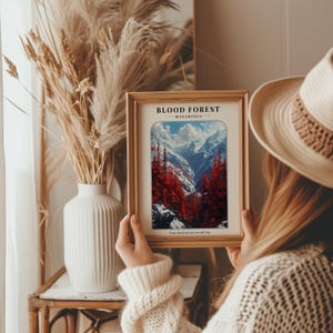 May include: A framed print of a mountain landscape with a red forest in the foreground. The print has the text "BLOOD FOREST - MACEDONIA - From blood and ash, we will rise."