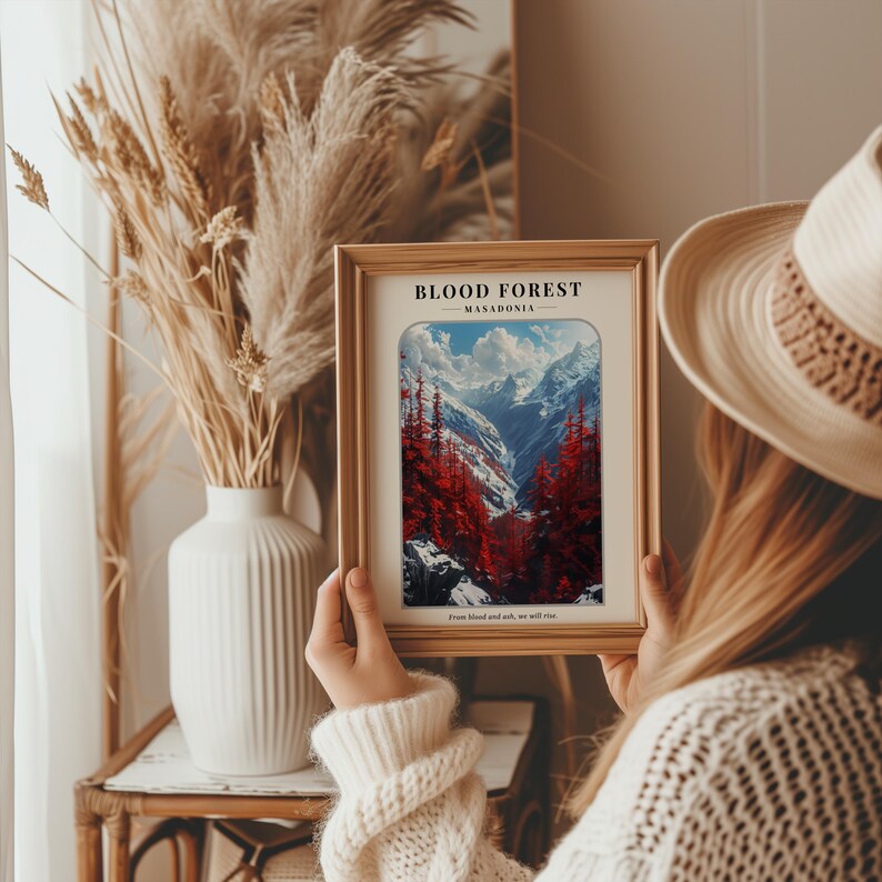 May include: A framed print of a mountain landscape with a red forest in the foreground. The print has the text "BLOOD FOREST - MACEDONIA - From blood and ash, we will rise."