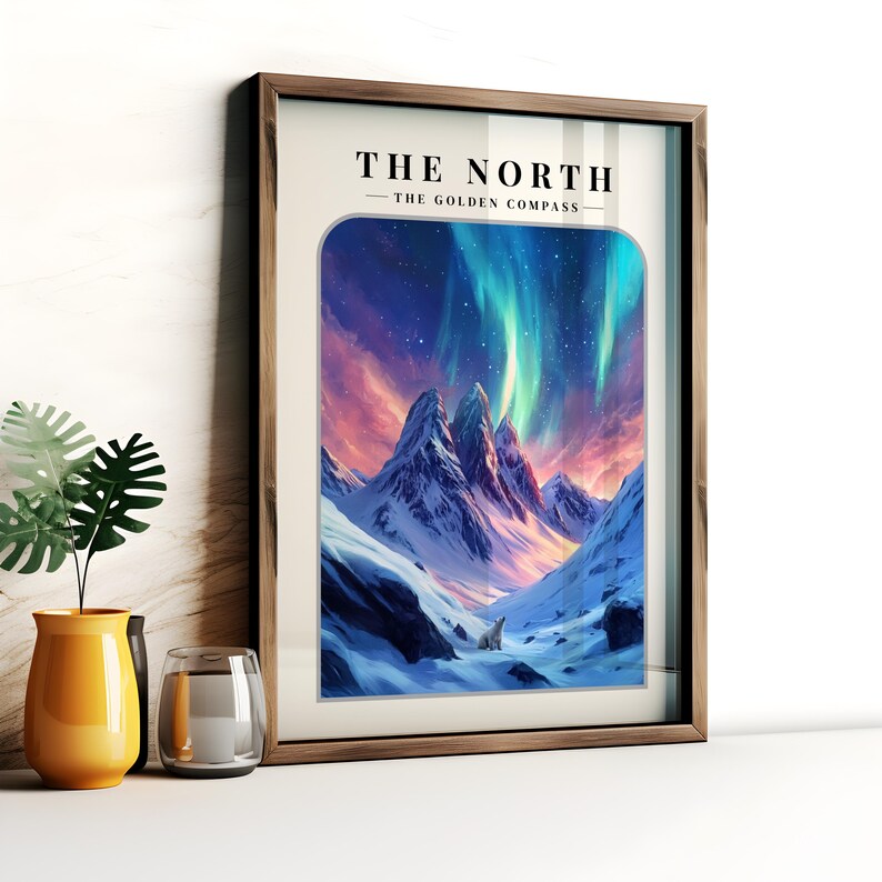 May include: A framed print with a mountain scene and a white polar bear in the foreground. The sky is a vibrant blue with green and pink aurora borealis. The text "THE NORTH - THE GOLDEN COMPASS" is at the top of the print.