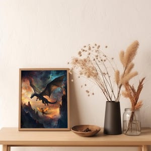 K&ouml;nnte beinhalten: Ein gerahmter Druck eines schwarzen und blauen Drachen, der durch einen sternenklaren Himmel fliegt, mit einem kleineren, goldenen Drachen, der hinter ihm fliegt. Die Drachen fliegen &uuml;ber eine felsige Landschaft.