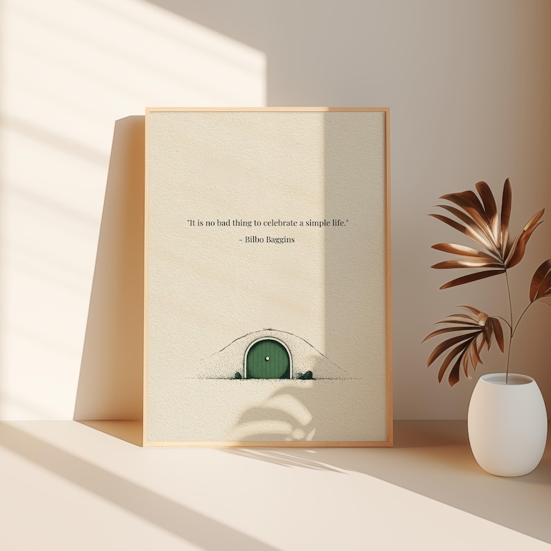 May include: Framed art print featuring a whimsical illustration of a hobbit hole with a green door. The print includes the quote "It is no bad thing to celebrate a simple life." by Bilbo Baggins. The frame is a light wood color.