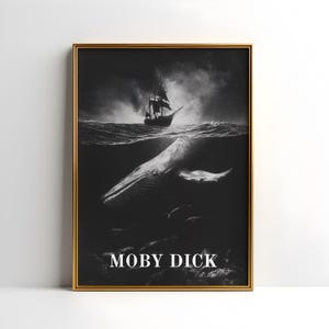 Op de afbeelding: Zwart-wit ingelijste print met een walvis onder water en een zeilschip aan de oppervlakte. De tekst "MOBY DICK" staat onderaan de afbeelding. Het kunstwerk zit in een gouden lijst.