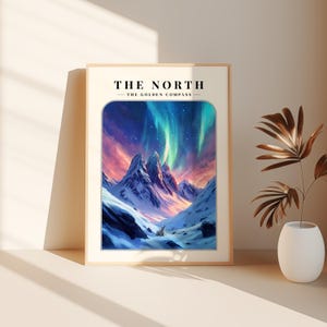 May include: A framed print with a mountain range and a polar bear in the foreground. The sky is filled with pink, blue, and green aurora borealis. The text "THE NORTH - THE GOLDEN COMPASS" is at the top of the print.