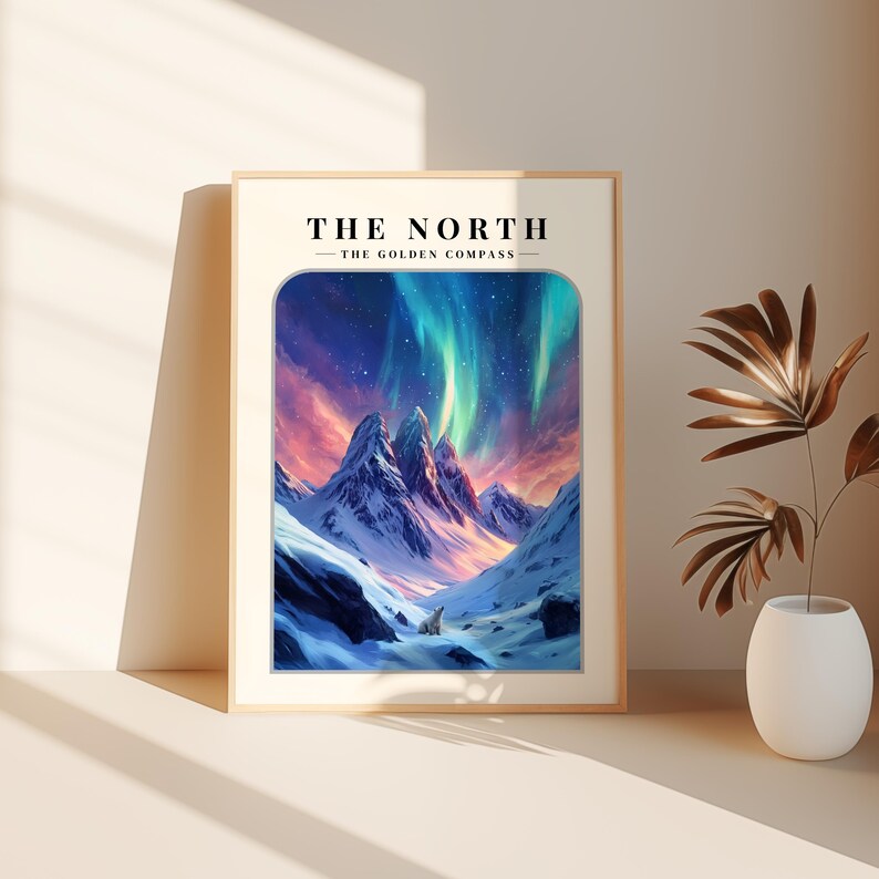 May include: A framed print with a mountain range and a polar bear in the foreground. The sky is filled with pink, blue, and green aurora borealis. The text "THE NORTH - THE GOLDEN COMPASS" is at the top of the print.
