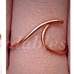 May include: A gold wave ring, a simple and delicate piece of jewelry.
