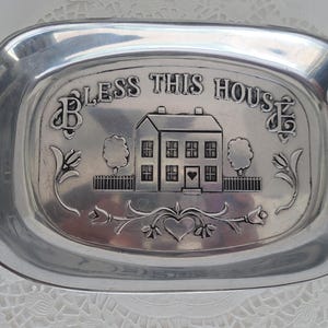May include: Silver tray with an engraved design of a house and the words "Bless This House".