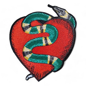 May include: An embroidered iron-on patch featuring a green and black snake wrapped around a red heart. The snake has yellow and white stripes.