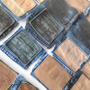May include: A collection of denim patches with leather labels, featuring the Levi Strauss & Co. logo and text. Some labels display the "501" designation. The patches are in shades of blue and brown, with visible stitching.