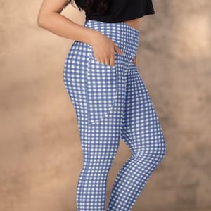 May include: A black short-sleeved crop top paired with blue and white gingham patterned leggings. The leggings feature a high-waisted design with visible side pockets on the hip area. The outfit is completed with black athletic sneakers.