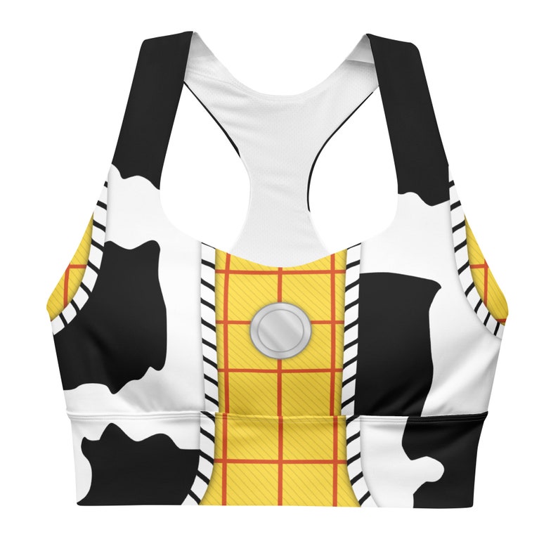 May include: A white and black cow print sports bra with a yellow and red plaid pattern on the front. The bra has a black racerback design.