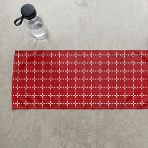 Pu&ograve; includere: Un tappetino da yoga rosso con un motivo geometrico bianco di linee e punti che si intersecano. Una bottiglia d'acqua trasparente con un tappo nero &egrave; nell'angolo in alto a sinistra. Il tappetino &egrave; rettangolare.