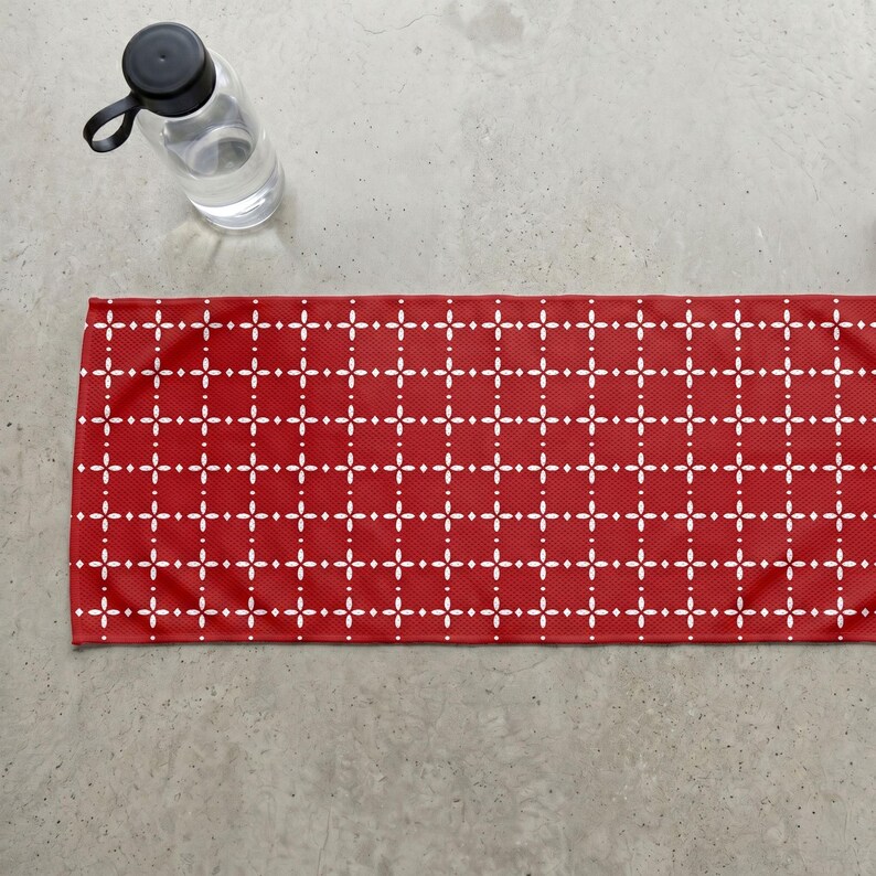 Pu&ograve; includere: Un tappetino da yoga rosso con un motivo geometrico bianco di linee e punti che si intersecano. Una bottiglia d'acqua trasparente con un tappo nero &egrave; nell'angolo in alto a sinistra. Il tappetino &egrave; rettangolare.