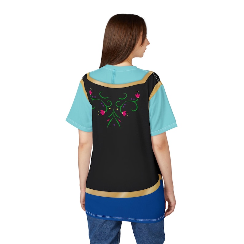 May include: A light blue and black t-shirt with a floral design. The shirt has a gold trim and a blue bottom. The back of the shirt features a black panel with a floral design in pink and green.