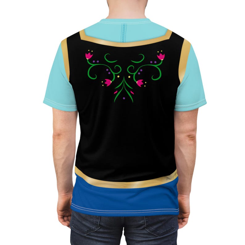 May include: A light blue t-shirt with a black vest overlay featuring a gold trim and floral design. The vest has a blue and gold trim. The shirt has a blue and gold trim at the bottom.