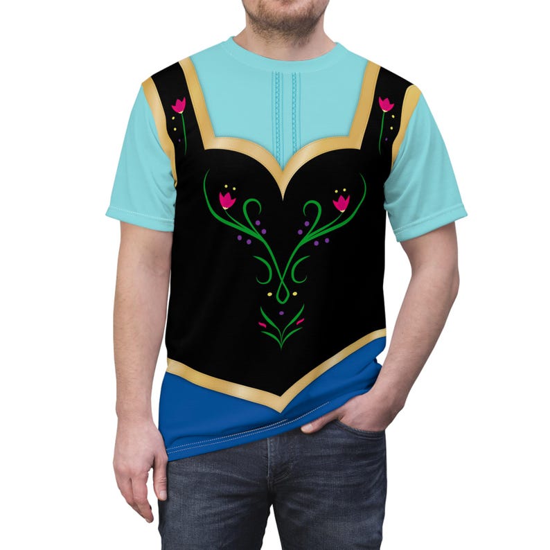 May include: A light blue t-shirt featuring a black bodice design with gold trim and floral accents. The shirt has a blue neckline and sleeves, and is worn by a person.
