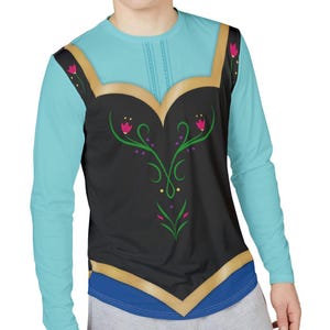 May include: A long-sleeve shirt featuring a light blue bodice and sleeves with a black vest-like overlay. The black section is decorated with green floral scrollwork, pink tulip-like flowers, and gold trim along the neckline and hem.
