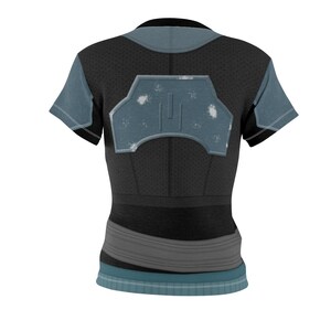 May include: A short-sleeved t-shirt in black with blue-grey accents. The back features a central blue-grey panel with a distressed, weathered texture and a geometric shape. A wide grey band wraps around the waist, and the hem is finished with a blue-grey trim.