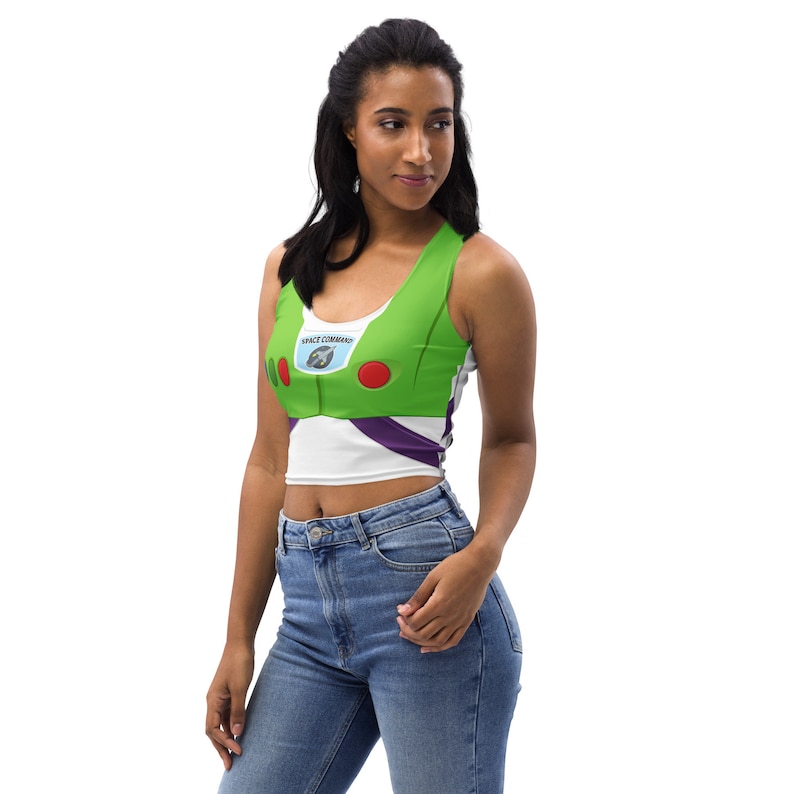 May include: A green, white, and purple crop top with a design inspired by the character Buzz Lightyear. The top features the words "SPACE COMMAND" and red and green accents. The top is sleeveless and made of a soft material.