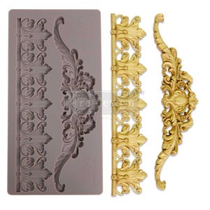 May include: A silicone mold for baking and decorating cakes. The mold features three ornate designs, including a border, a large floral motif, and a smaller floral motif. The mold is gray and has the text "REDESIGN WITH PRIMA.COM" printed on it.
