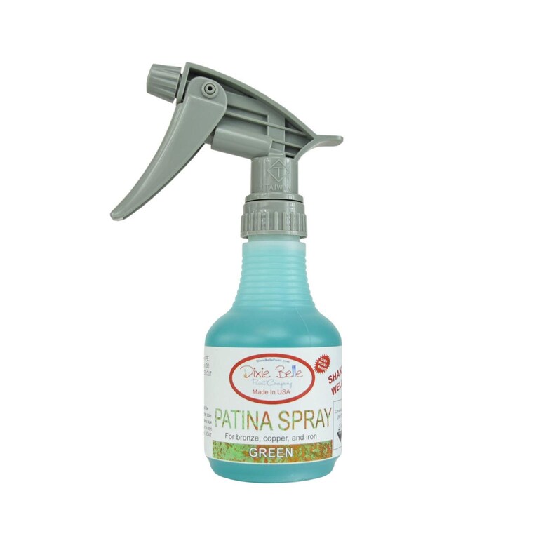 May include: A green Dixie Belle Patina Spray bottle with a gray spray nozzle. The bottle label reads "Patina Spray" and "For bronze, copper, and iron" and "Green".